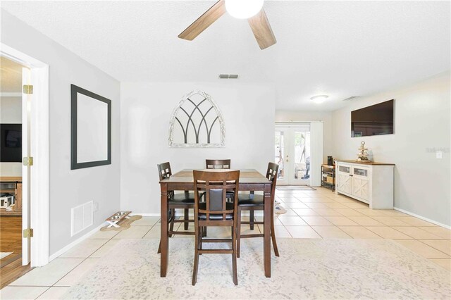 dining room with light tile patterned flooring, a ceiling fan, visible vents, and french doors