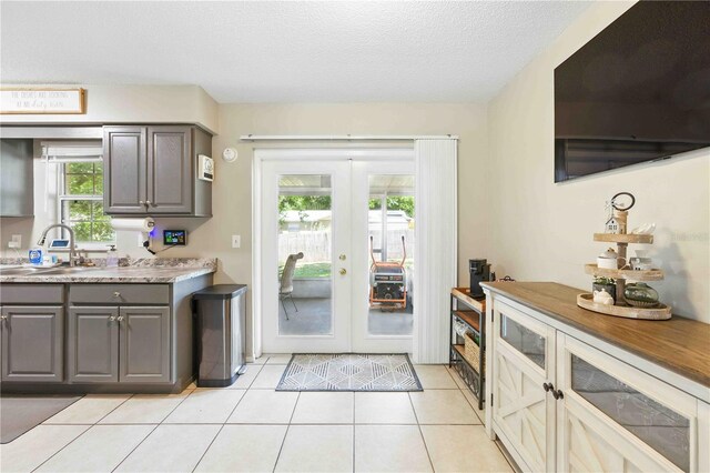 kitchen with french doors, gray cabinetry, light tile patterned floors, a sink, and light countertops