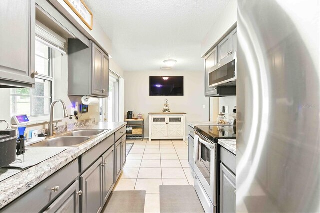 kitchen featuring a sink, appliances with stainless steel finishes, gray cabinets, and light tile patterned floors