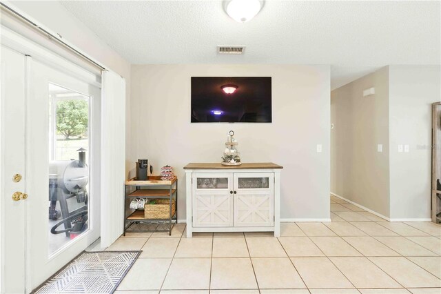 living area featuring light tile patterned floors, baseboards, a textured ceiling, and visible vents