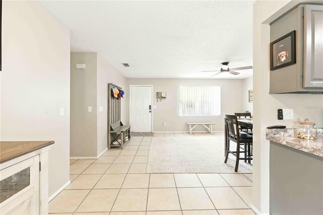 kitchen featuring a ceiling fan, visible vents, light stone countertops, light tile patterned floors, and baseboards