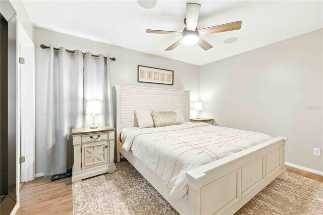 bedroom featuring a ceiling fan, baseboards, and light wood finished floors