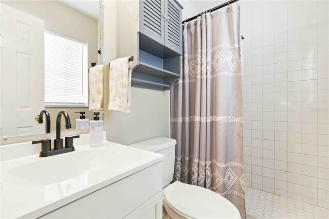 full bathroom with vanity, toilet, and tiled shower