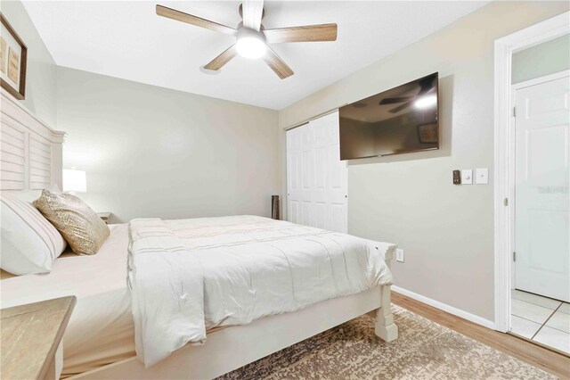 bedroom featuring baseboards, a ceiling fan, wood finished floors, and a closet