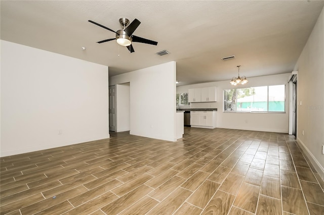 unfurnished living room with ceiling fan with notable chandelier, baseboards, visible vents, and wood finished floors