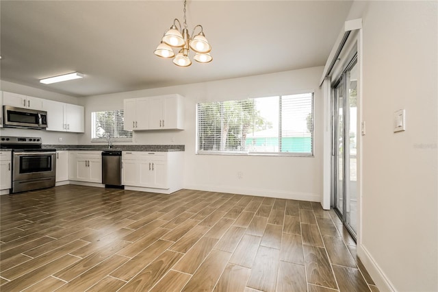 kitchen featuring an inviting chandelier, stainless steel appliances, dark wood-style floors, and white cabinets