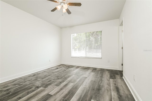 spare room featuring baseboards, ceiling fan, and dark wood-type flooring