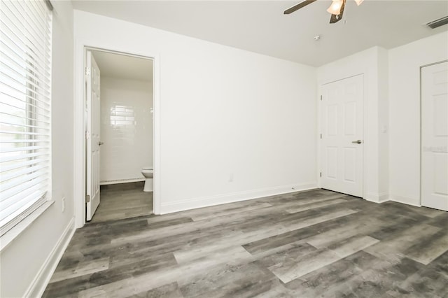 unfurnished bedroom with connected bathroom, visible vents, wood finished floors, and baseboards