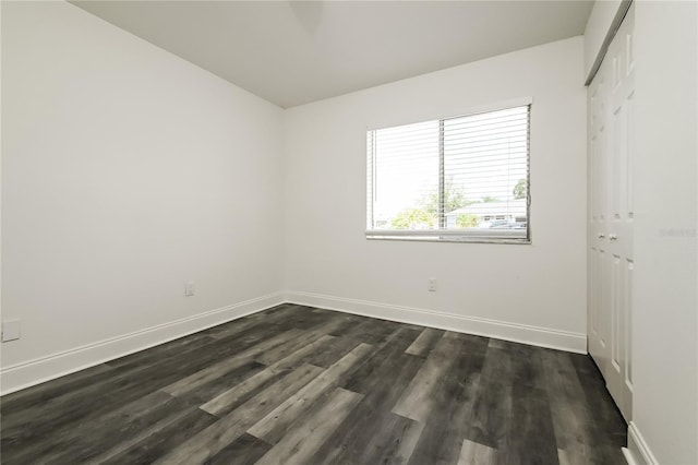 empty room with baseboards and dark wood-style floors