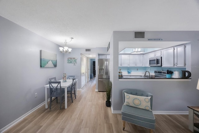 404 Hammock Pine Blvd Unit 404, Clearwater, FL 33761 - kitchen featuring visible vents, light wood-style flooring, appliances with stainless steel finishes, and a notable chandelier
