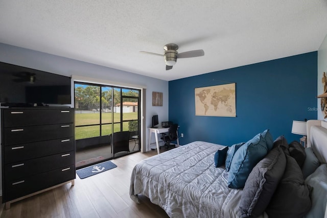 404 Hammock Pine Blvd Unit 404, Clearwater, FL 33761 - bedroom with ceiling fan, a textured ceiling, access to exterior, an accent wall, and wood finished floors