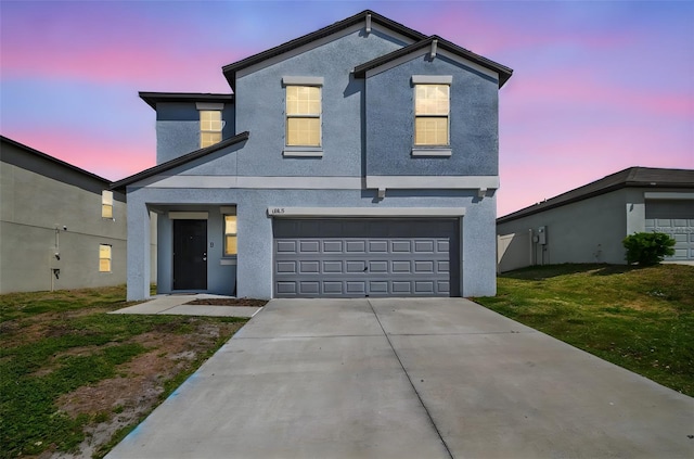 traditional-style house featuring a garage, stucco siding, concrete driveway, and a front yard
