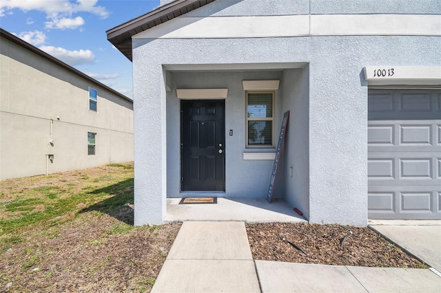doorway to property with a garage and stucco siding