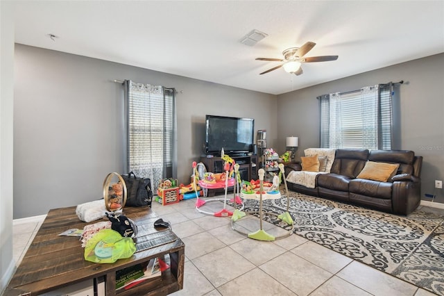 living area with tile patterned flooring, plenty of natural light, a ceiling fan, and visible vents