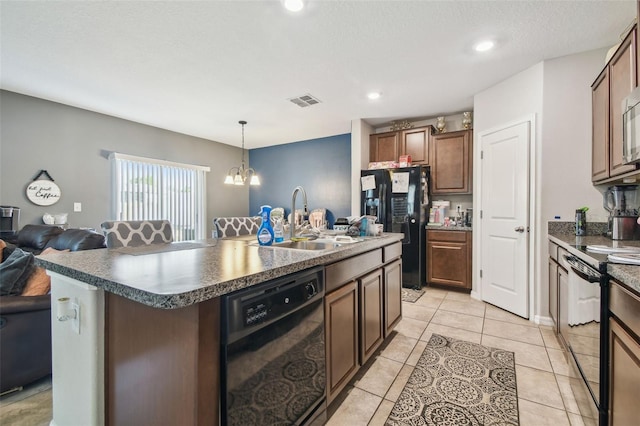 kitchen with a notable chandelier, a sink, a kitchen island with sink, open floor plan, and black appliances