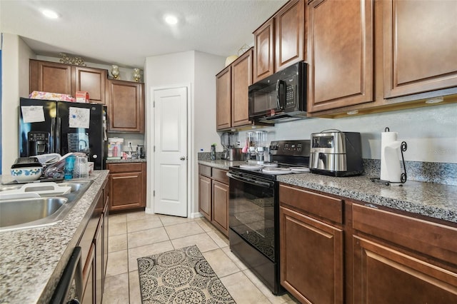 kitchen with a sink, light tile patterned floors, and black appliances