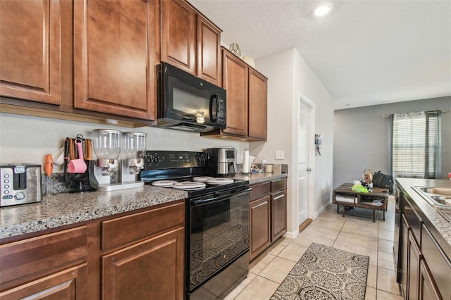 kitchen featuring brown cabinets, light tile patterned flooring, a sink, and black appliances