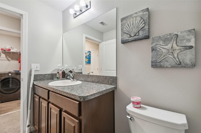 bathroom featuring visible vents, washer / clothes dryer, toilet, and vanity