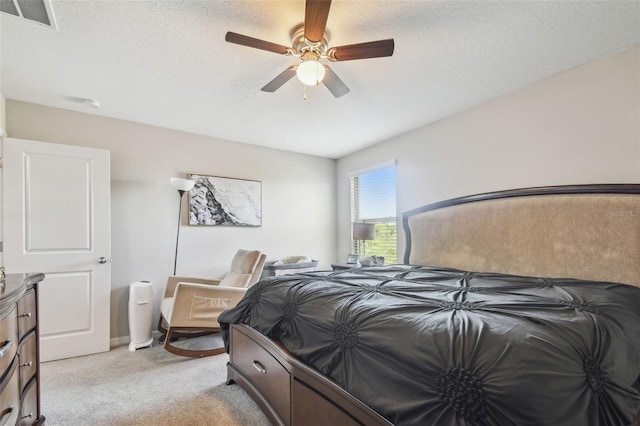 bedroom with ceiling fan, light colored carpet, a textured ceiling, and visible vents