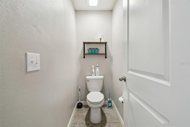 bathroom with toilet, baseboards, and tile patterned floors