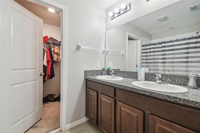 full bathroom with a sink, a spacious closet, double vanity, and visible vents