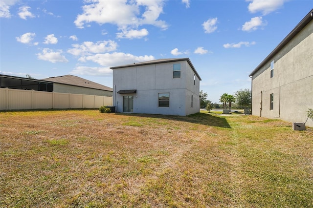 rear view of property with fence, stucco siding, and a lawn