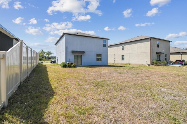 rear view of house featuring fence and a yard