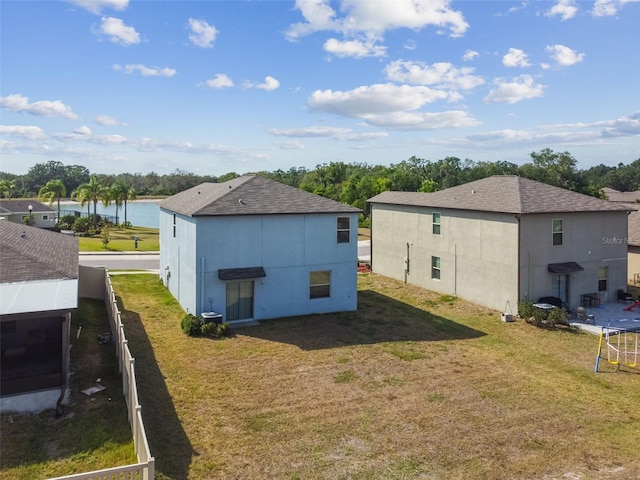 rear view of house with a water view and a yard