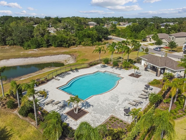 community pool with a patio, a water view, and fence
