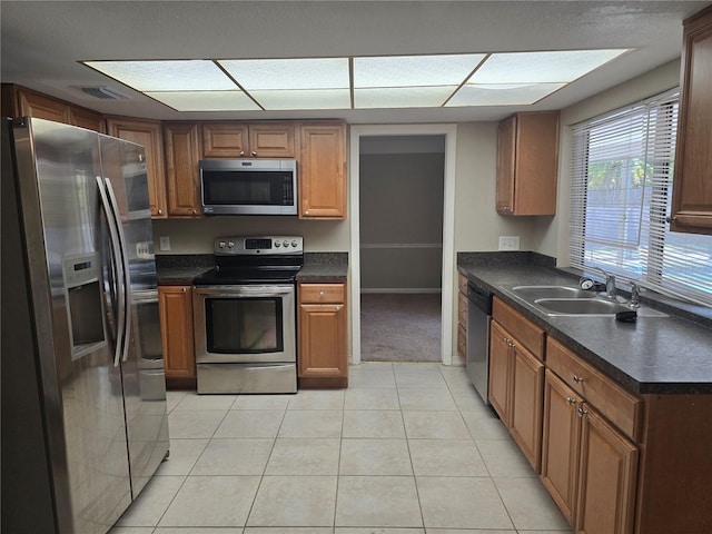 kitchen with dark countertops, appliances with stainless steel finishes, a sink, light tile patterned floors, and visible vents