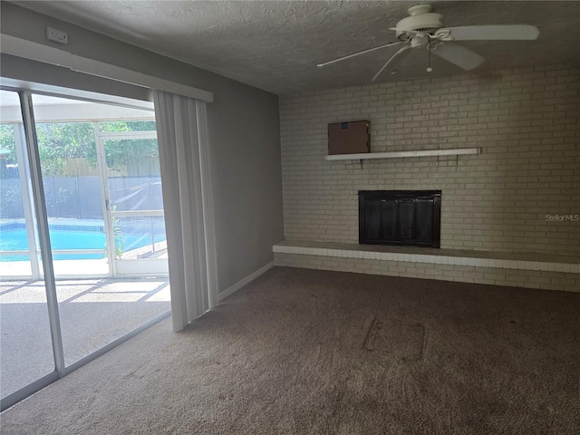 unfurnished living room with ceiling fan, a textured ceiling, a fireplace, baseboards, and carpet