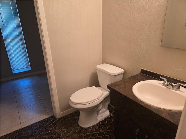 bathroom featuring vanity, a textured wall, and toilet