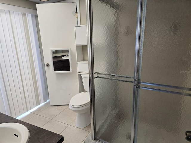 full bath with toilet, a shower stall, a sink, and tile patterned flooring