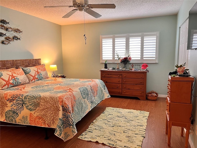 bedroom featuring a textured ceiling, wood finished floors, and a ceiling fan