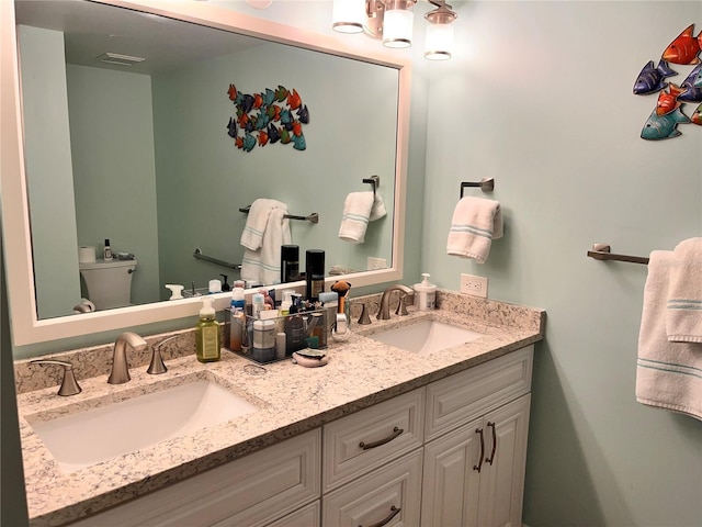 full bath with double vanity, toilet, visible vents, and a sink
