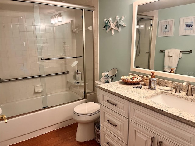 bathroom with toilet, vanity, combined bath / shower with glass door, and wood finished floors