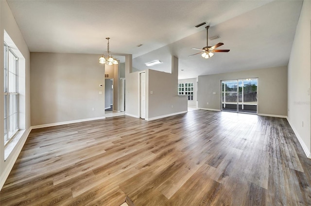 37437 Laurel Hammock Dr, Zephyrhills, FL 33541 - unfurnished living room with baseboards, vaulted ceiling, wood finished floors, and ceiling fan with notable chandelier