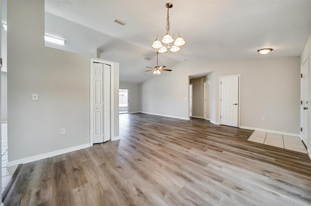 37437 Laurel Hammock Dr, Zephyrhills, FL 33541 - unfurnished living room with baseboards, ceiling fan with notable chandelier, wood finished floors, and lofted ceiling
