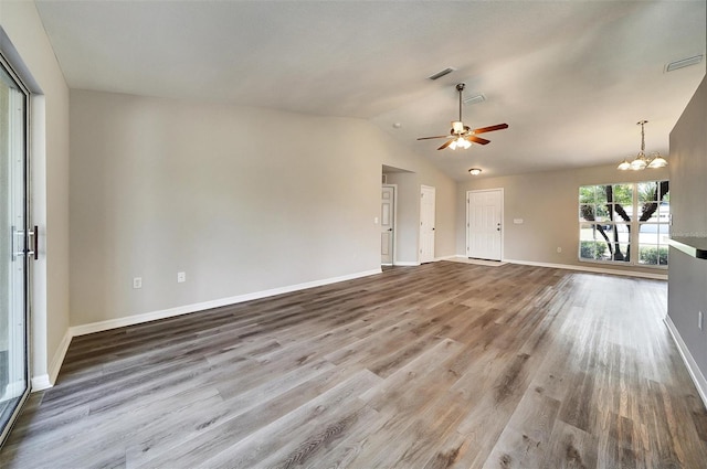 37437 Laurel Hammock Dr, Zephyrhills, FL 33541 - unfurnished living room with baseboards, lofted ceiling, wood finished floors, and ceiling fan with notable chandelier