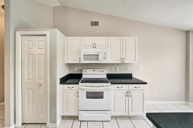 37437 Laurel Hammock Dr, Zephyrhills, FL 33541 - kitchen with dark countertops, light tile patterned floors, white cabinets, and white appliances