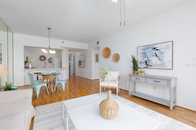 living area featuring a notable chandelier, light wood-type flooring, and visible vents