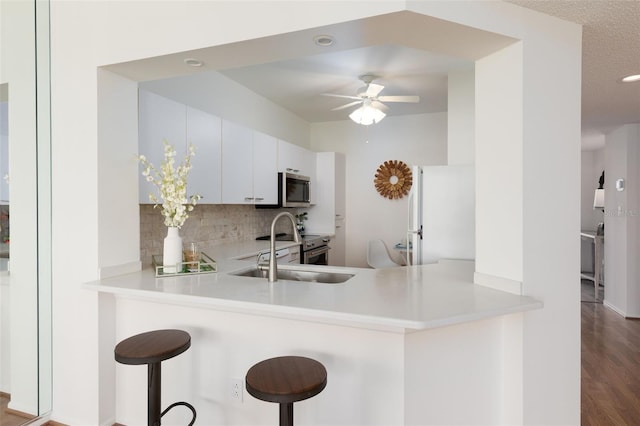 kitchen featuring a ceiling fan, stainless steel appliances, a peninsula, decorative backsplash, and light countertops