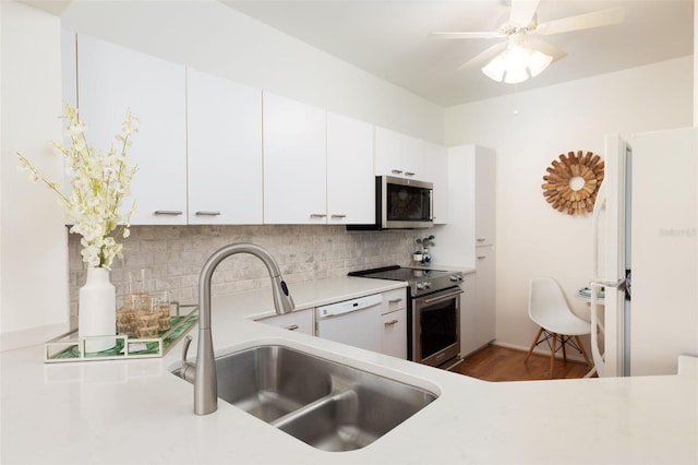 kitchen with a sink, stainless steel appliances, ceiling fan, backsplash, and light countertops