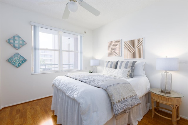 bedroom with baseboards, multiple windows, ceiling fan, and wood finished floors