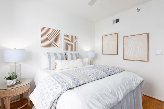 bedroom with baseboards, ceiling fan, visible vents, and wood finished floors