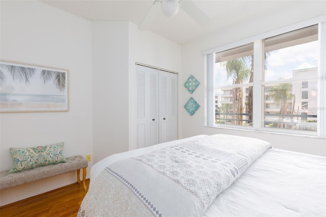 bedroom featuring multiple windows, a closet, ceiling fan, and wood finished floors