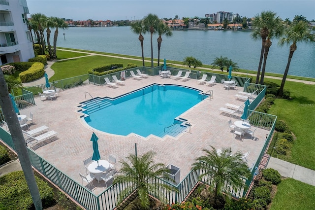 pool with a yard, a patio, a water view, and fence