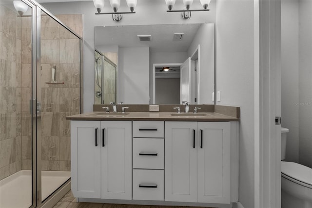 full bathroom featuring ceiling fan, visible vents, a stall shower, a sink, and toilet