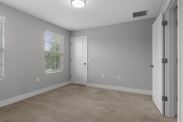 unfurnished bedroom with baseboards, visible vents, and light carpet