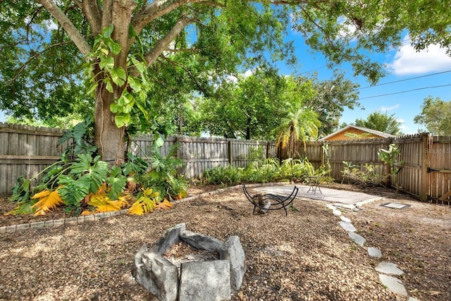 view of yard featuring a fenced backyard, a patio, and an outdoor fire pit